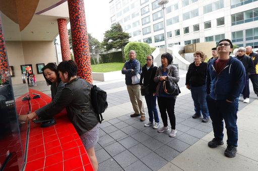 In this Thursday, Aug. 23, 2018 photo, a woman who did not give her name, second from left, buys tickets for the movie Crazy Rich Asians for her and her aunt at a movie theater in Daly City, Calif. When